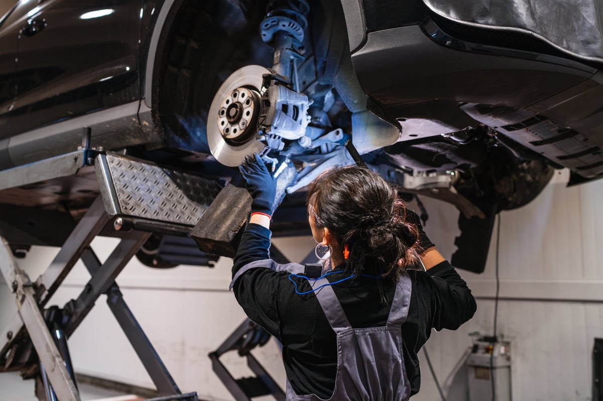 Mechanic inspecting brakes under a lifted vehicle