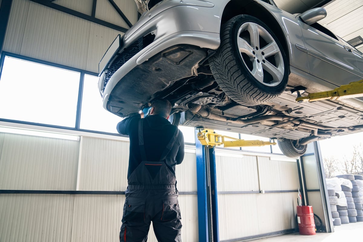 Mechanic checking a car suspension on a lift